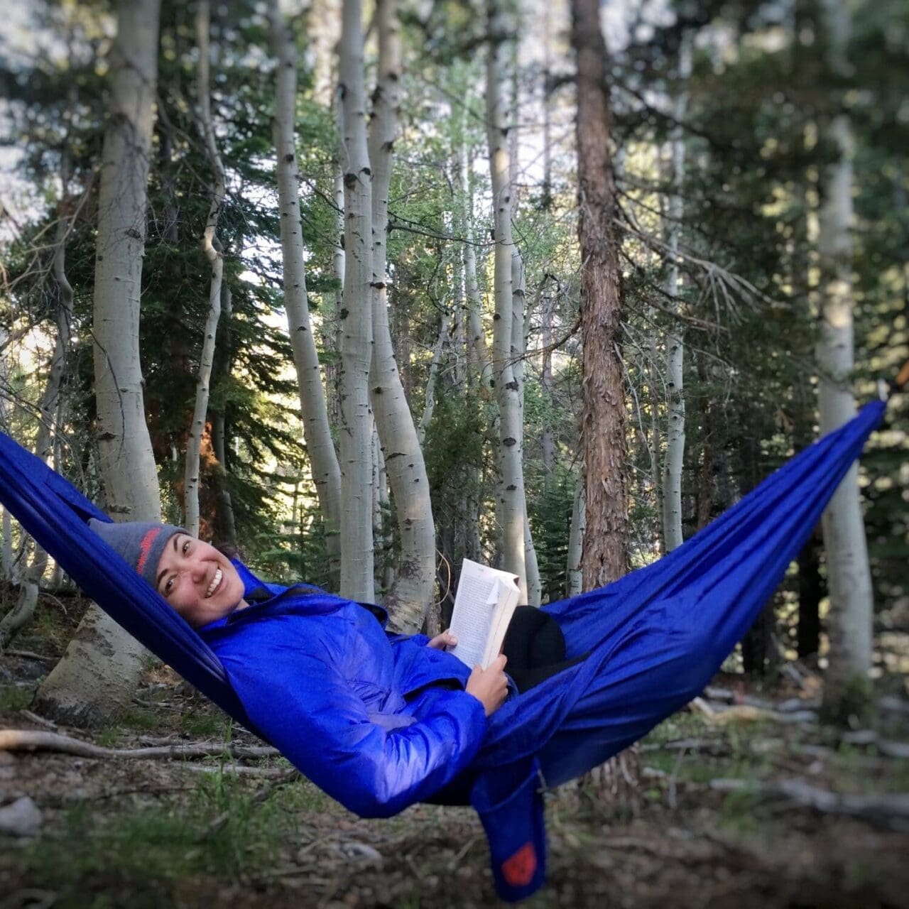 Outdoor Lifestyle Photograph of a person reading in a hammock in the woods
